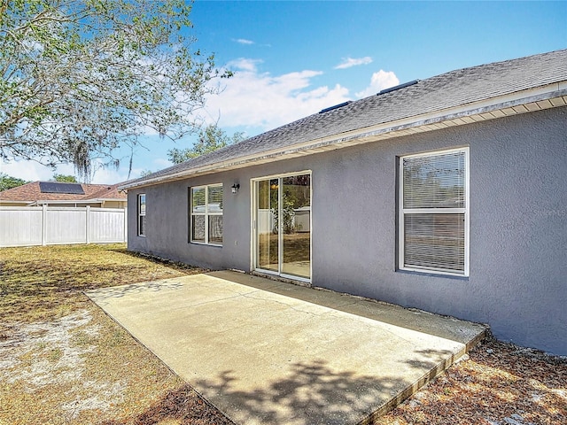 back of property with fence, stucco siding, and a patio area