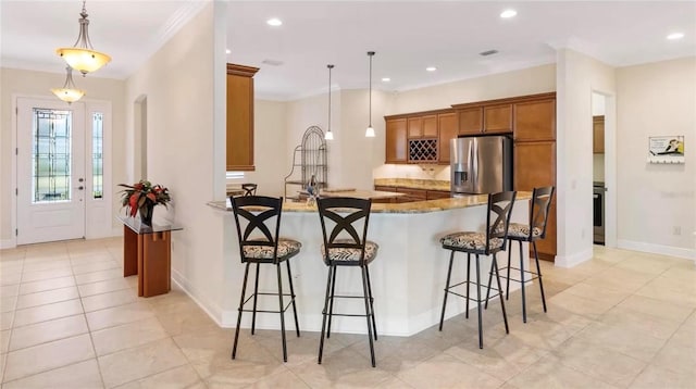871 Iron Oak Way, The Villages, FL 32163 - kitchen featuring brown cabinetry, a kitchen bar, stainless steel refrigerator with ice dispenser, light tile patterned floors, and a peninsula
