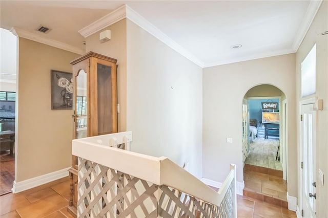 hallway featuring arched walkways, baseboards, an upstairs landing, and ornamental molding