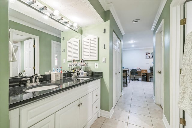 bathroom featuring baseboards, ornamental molding, a sink, and tile patterned flooring