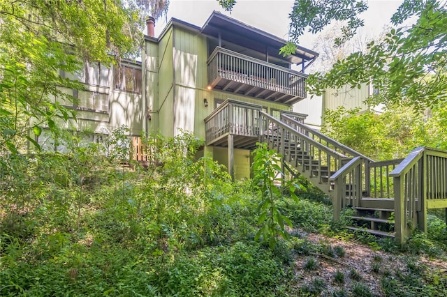 rear view of property with a deck, a chimney, stairs, and a balcony