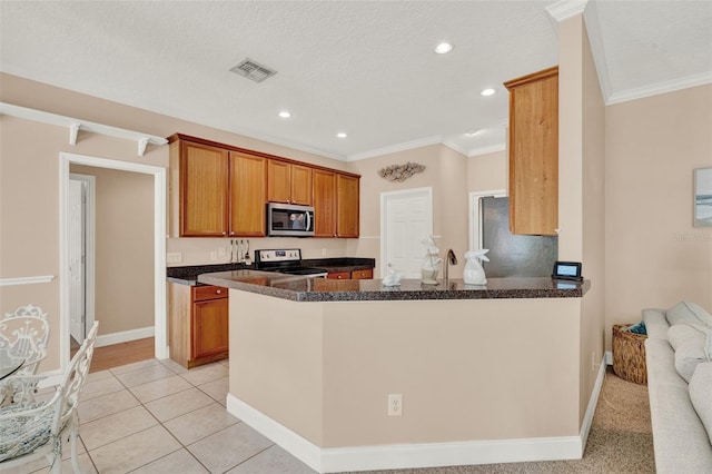 kitchen featuring stainless steel microwave, range with electric stovetop, ornamental molding, freestanding refrigerator, and brown cabinets