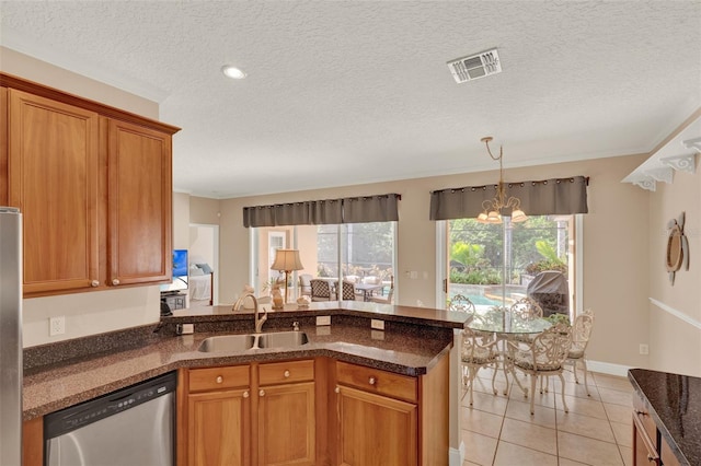 kitchen featuring a sink, stainless steel dishwasher, brown cabinetry, a peninsula, and light tile patterned floors