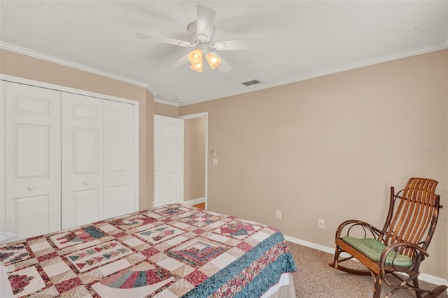 carpeted bedroom with a closet, baseboards, a ceiling fan, and crown molding