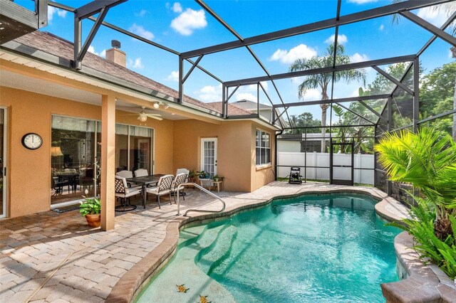view of swimming pool featuring a patio, a ceiling fan, and glass enclosure