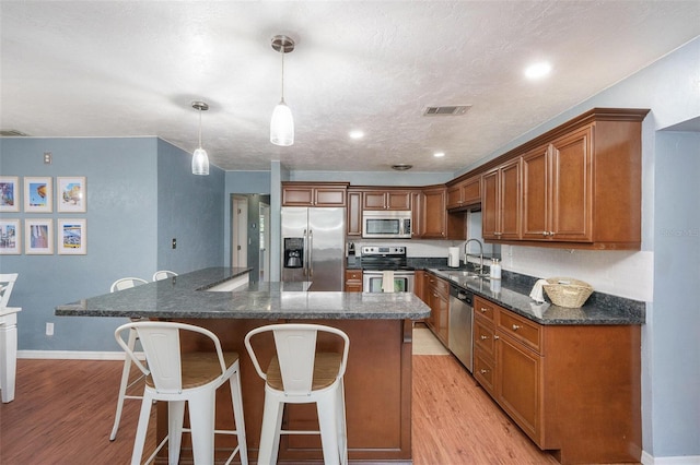 6801 16th St N, Saint Petersburg, FL 33702 - kitchen with a sink, light wood finished floors, a kitchen bar, a kitchen island, and appliances with stainless steel finishes