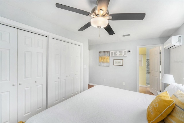 6801 16th St N, Saint Petersburg, FL 33702 - bedroom featuring an AC wall unit, ensuite bath, ceiling fan, visible vents, and two closets