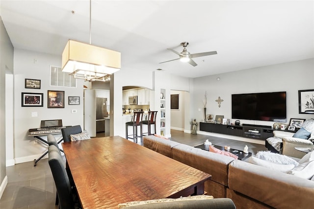 tiled living area with arched walkways, ceiling fan, visible vents, and baseboards