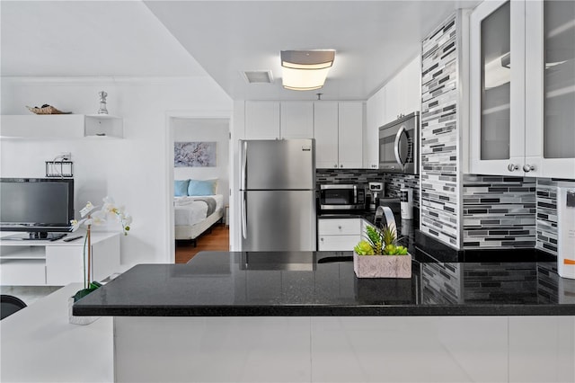 kitchen featuring white cabinets, stainless steel appliances, tasteful backsplash, visible vents, and glass insert cabinets