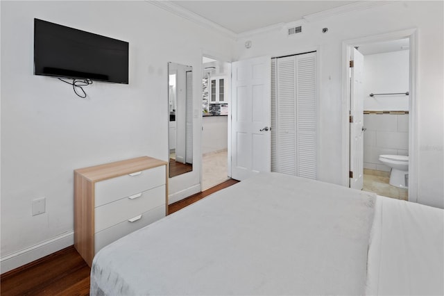 bedroom featuring ensuite bathroom, visible vents, wood finished floors, a closet, and ornamental molding