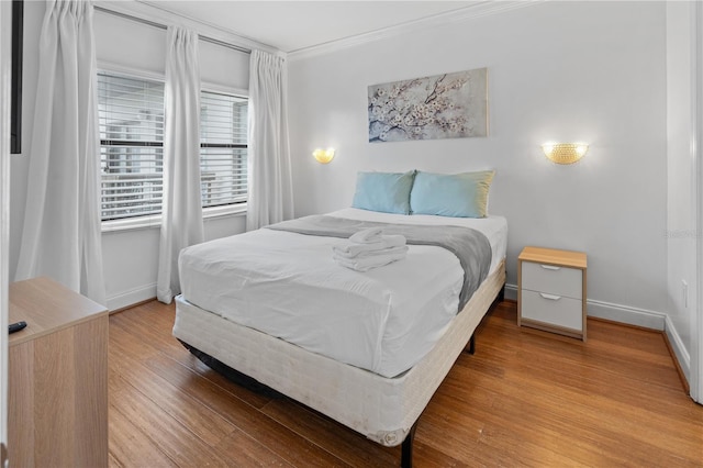 bedroom with crown molding, baseboards, and wood finished floors