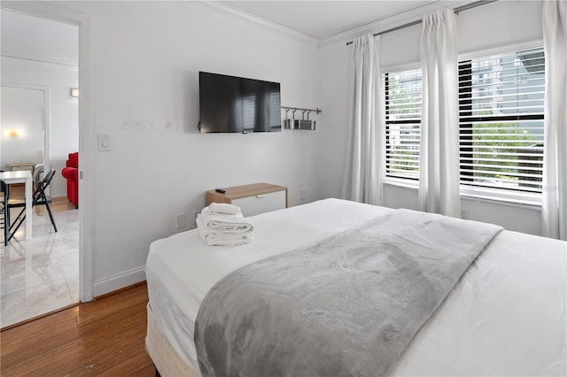 bedroom featuring baseboards, ornamental molding, and wood finished floors