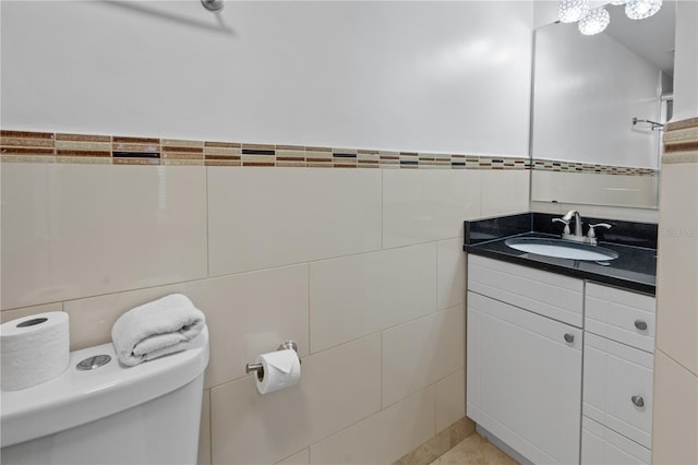 bathroom with wainscoting, tile walls, vanity, and toilet