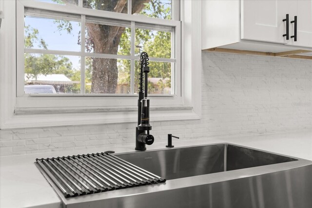 2014 10th St NW, Winter Haven, FL 33881 - room details featuring light countertops, a sink, backsplash, and white cabinetry