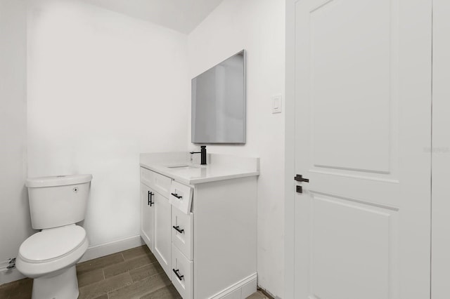 2014 10th St NW, Winter Haven, FL 33881 - bathroom featuring toilet, wood finish floors, baseboards, and vanity