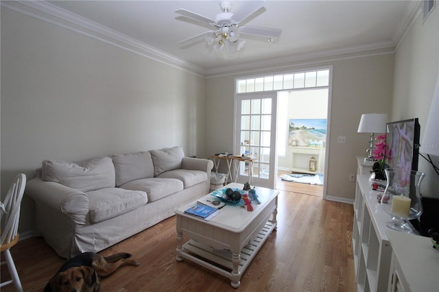 living room with crown molding, light wood-style flooring, a ceiling fan, baseboards, and visible vents