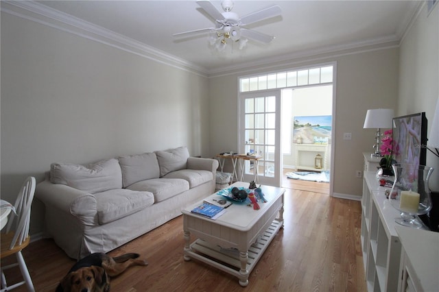 living room with crown molding, baseboards, ceiling fan, and wood finished floors