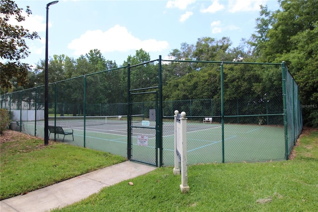 view of sport court with a lawn, fence, and a gate
