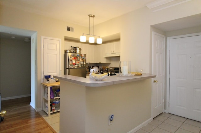 280 Celebration Blvd Unit 208, Kissimmee, FL 34747 - kitchen with freestanding refrigerator, under cabinet range hood, a peninsula, white cabinets, and light countertops
