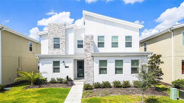 modern home featuring a front lawn, stucco siding, and stone siding