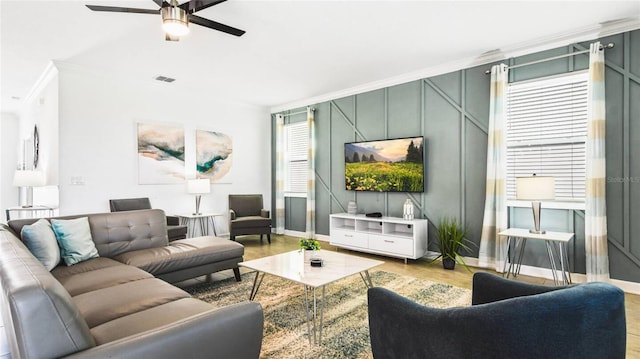 living area with crown molding, a ceiling fan, baseboards, wood finished floors, and visible vents