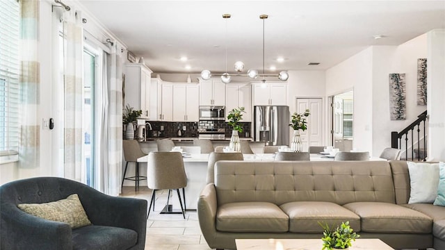 living room with plenty of natural light, light tile patterned floors, and stairway