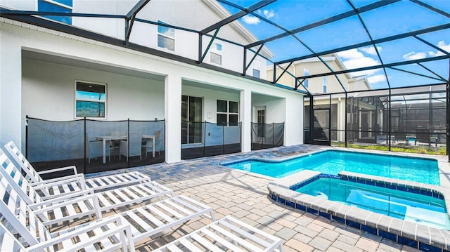 view of swimming pool featuring glass enclosure, a patio, and a pool with connected hot tub