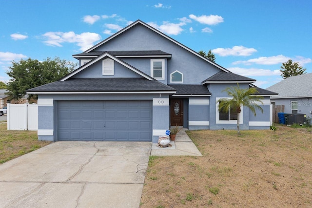 traditional home with an attached garage, stucco siding, fence, concrete driveway, and a front lawn