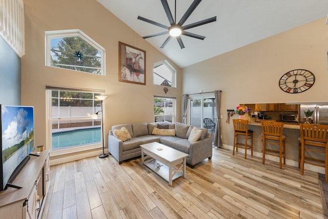 living area featuring light wood-style flooring, a ceiling fan, and high vaulted ceiling