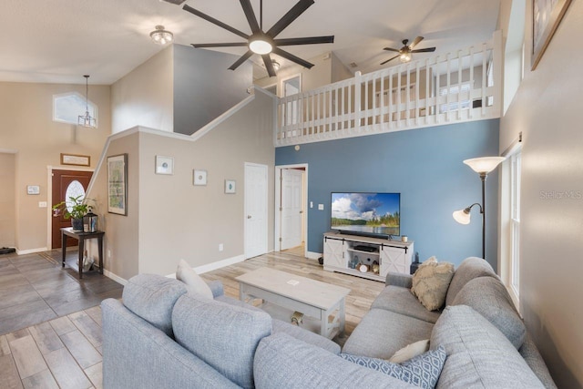 living room with a ceiling fan, baseboards, high vaulted ceiling, and wood finished floors