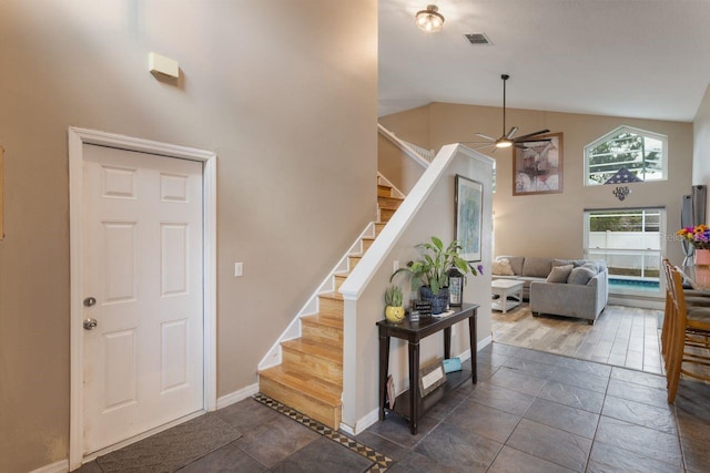 foyer entrance with high vaulted ceiling, visible vents, baseboards, ceiling fan, and stairs