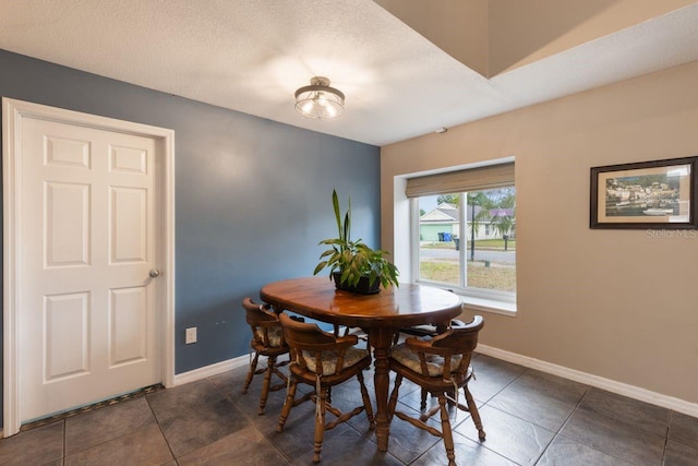dining room with dark tile patterned floors and baseboards