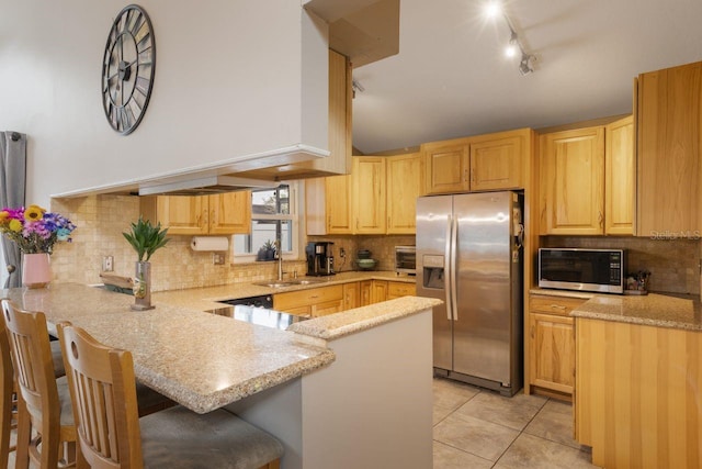 kitchen featuring a sink, a peninsula, light tile patterned flooring, decorative backsplash, and appliances with stainless steel finishes