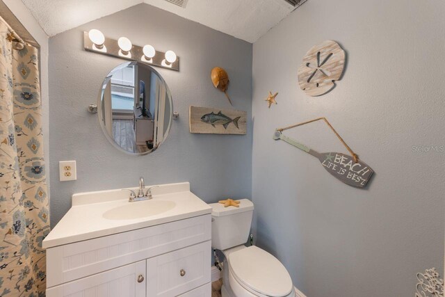 bathroom with toilet, lofted ceiling, and vanity