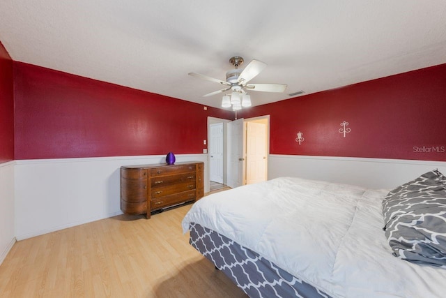 bedroom with a ceiling fan, visible vents, and wood finished floors