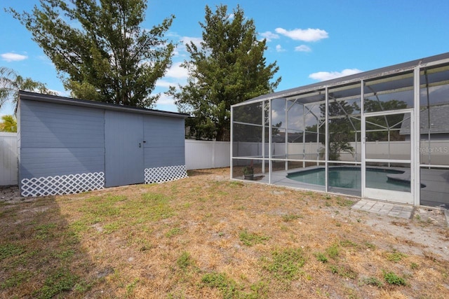 view of yard with an outdoor structure, a fenced backyard, a shed, a fenced in pool, and glass enclosure