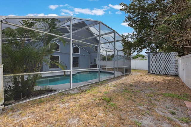 view of pool with a fenced backyard, a fenced in pool, and glass enclosure