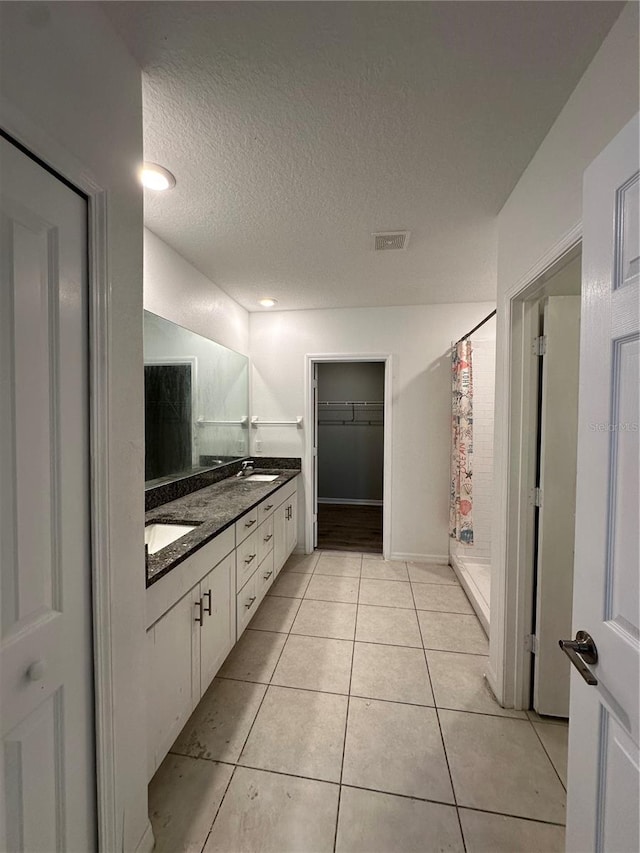13344 Great Plains Dr S, Riverview, FL 33579 - full bathroom featuring visible vents, double vanity, a textured ceiling, tile patterned floors, and a shower stall