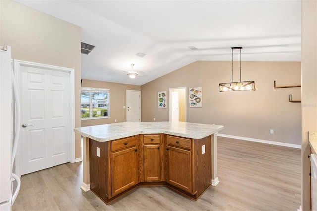 kitchen with visible vents, vaulted ceiling, brown cabinets, freestanding refrigerator, and light wood finished floors
