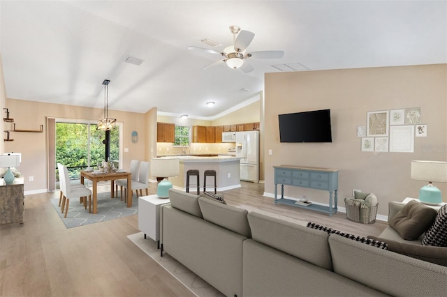 living room featuring a ceiling fan, vaulted ceiling, plenty of natural light, and light wood finished floors