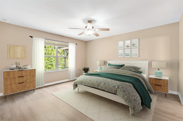 bedroom featuring baseboards, ceiling fan, and light wood-style flooring