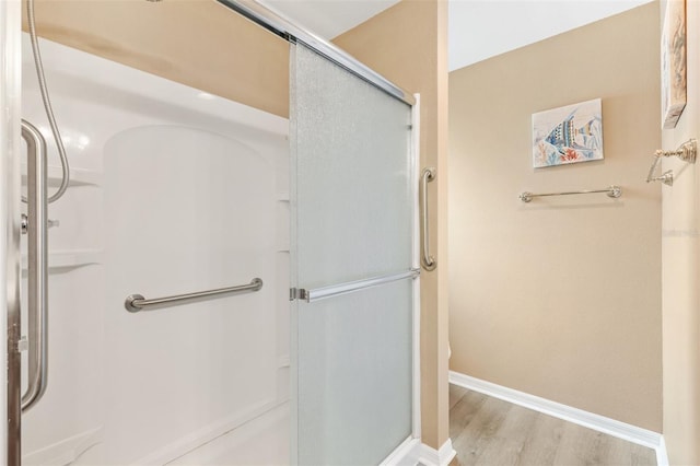 full bathroom featuring baseboards, wood finished floors, and a shower stall