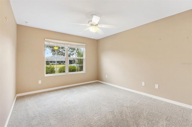 carpeted empty room with baseboards and a ceiling fan