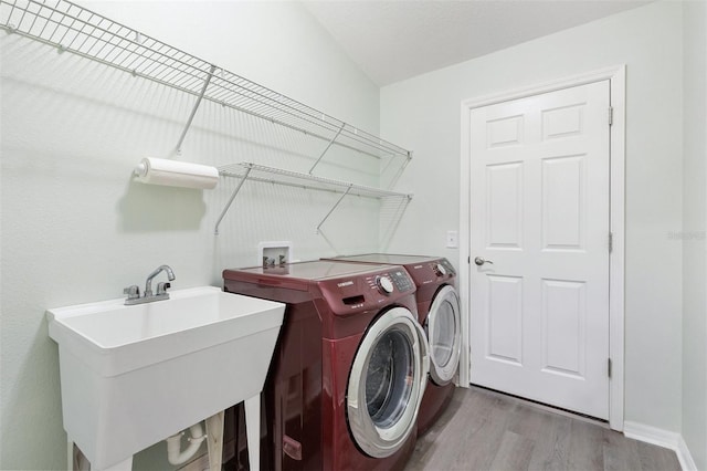 laundry room featuring washer and dryer, laundry area, a sink, and wood finished floors