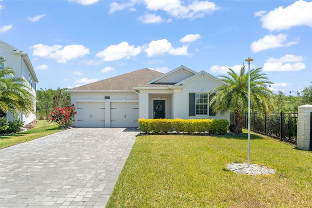 ranch-style home featuring fence, an attached garage, a front lawn, stucco siding, and decorative driveway