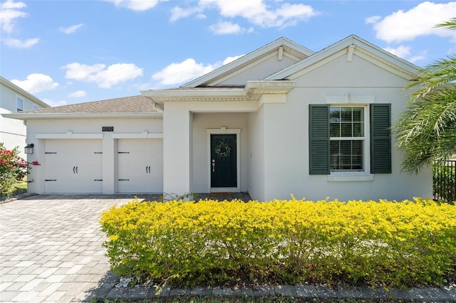 view of front facade with decorative driveway, a garage, and stucco siding