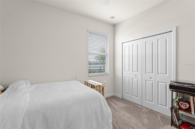 bedroom featuring baseboards, a ceiling fan, a closet, and light colored carpet