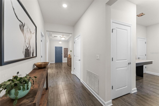 corridor with visible vents, dark wood-style flooring, and baseboards