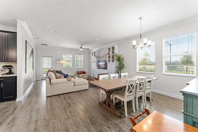 dining room featuring ceiling fan with notable chandelier, baseboards, light wood-type flooring, visible vents, and ornamental molding