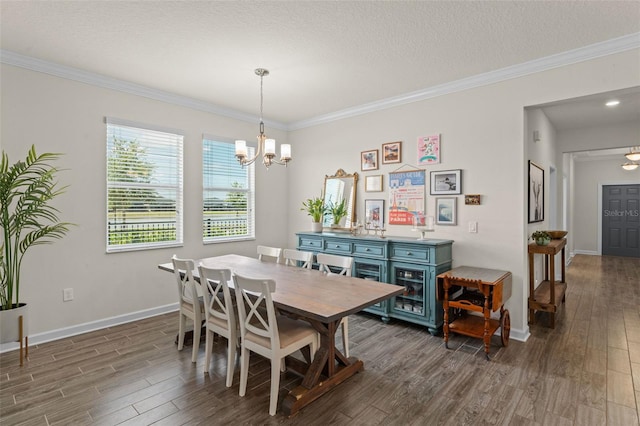 dining space featuring a textured ceiling, wood finished floors, baseboards, a chandelier, and ornamental molding